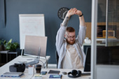 Man stretching at his desk.